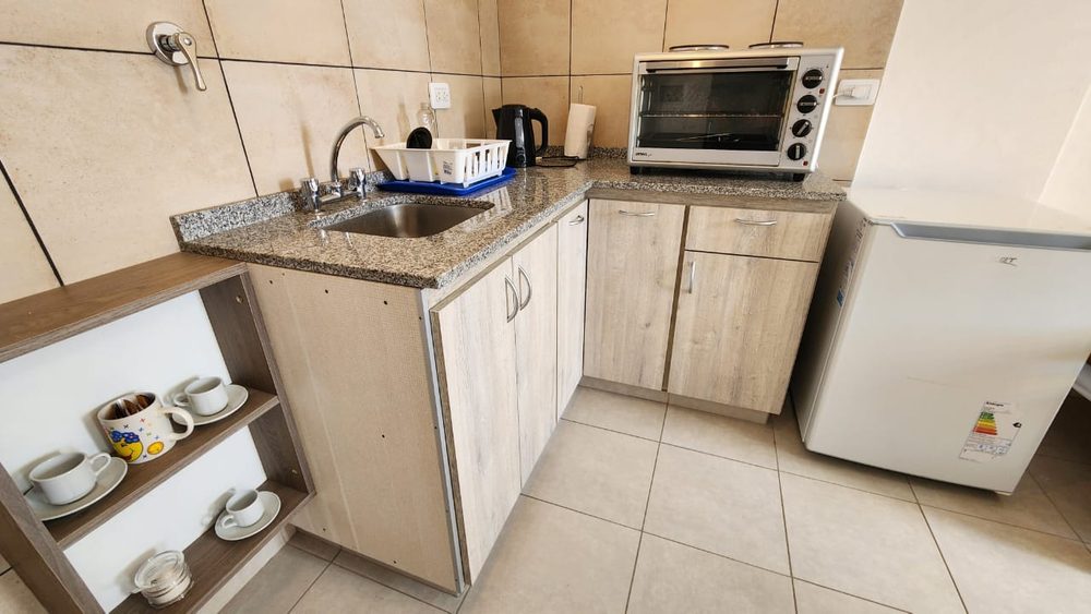 Cocina con mesada de granito, horno eléctrico y heladera